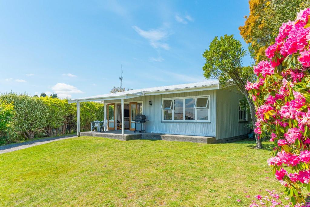 a house with a yard with pink flowers at Lakeview Cottage - Rainbow Point Holiday Home in Taupo