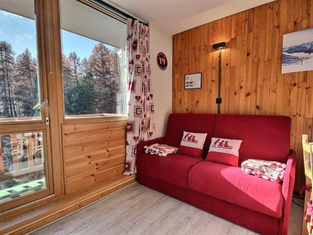 - un canapé rouge dans une chambre avec une grande fenêtre dans l'établissement Studio divisible au pied des pistes avec balcon, WiFi et lave-linge - FR-1-455-250, à La Plagne Tarentaise