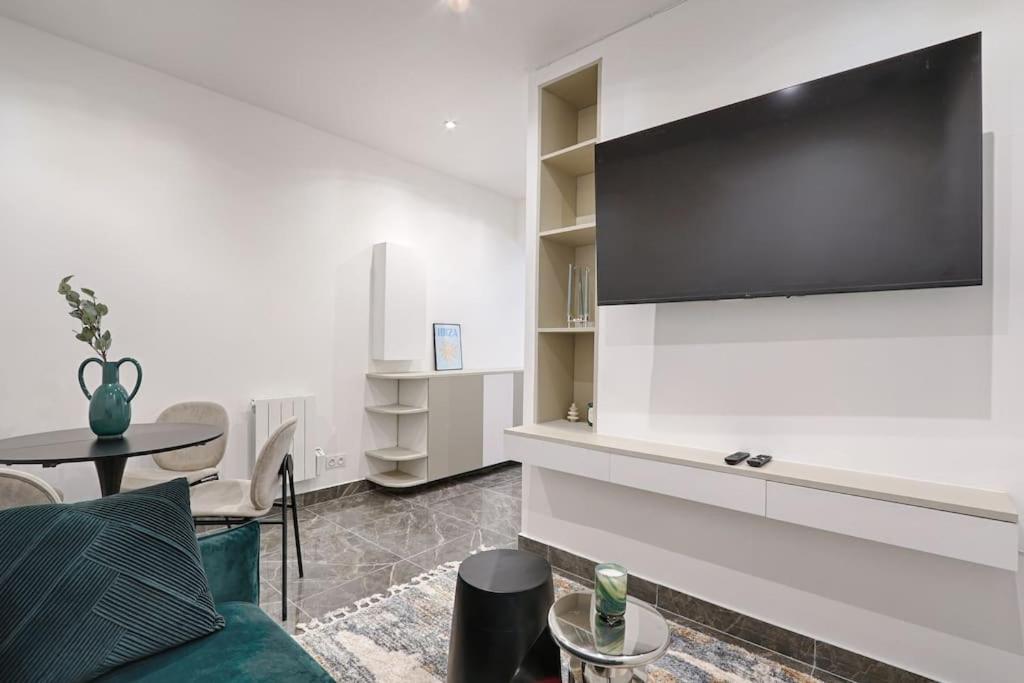 un salon avec un canapé et une télévision sur un mur dans l'établissement Buttes Chaumont Charming Apartment 4P, à Paris
