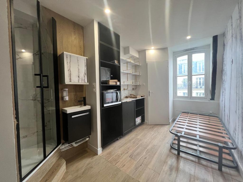 un salon avec une grande fenêtre et une chambre avec un banc dans l'établissement Batignolles, Montmartre Chambre 12m2 , Metro 13 et 14, à Paris