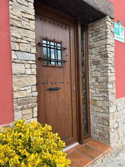 a wooden door of a building with flowers in front at Casa el sabinar in Anchuela del Campo