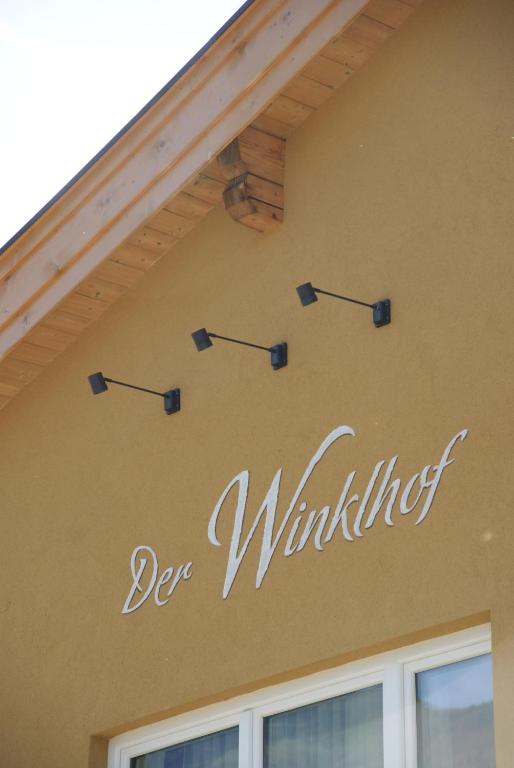 a sign on the side of a house with arrows on it at Der Winklhof in Saalfelden am Steinernen Meer