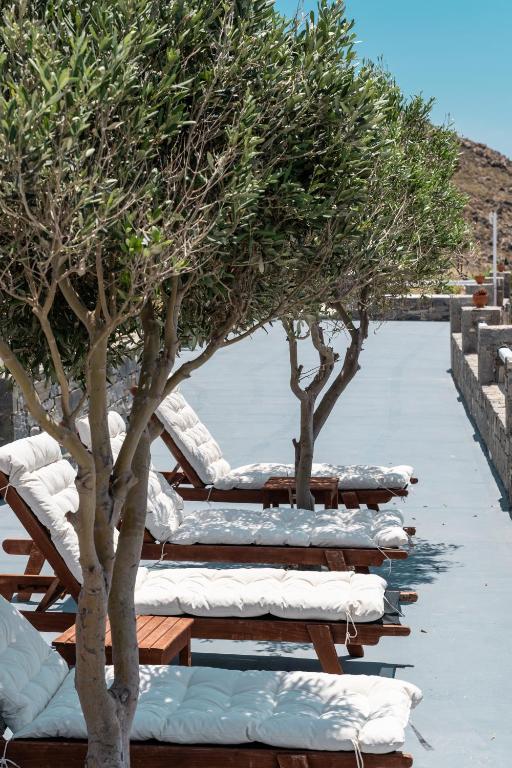 a row of lounge chairs under trees on a patio at Astrio Suites in Livadi
