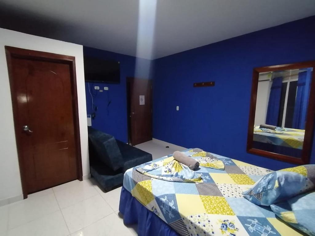 a blue bedroom with a bed and a mirror at Hotel Emperador in Jamundí