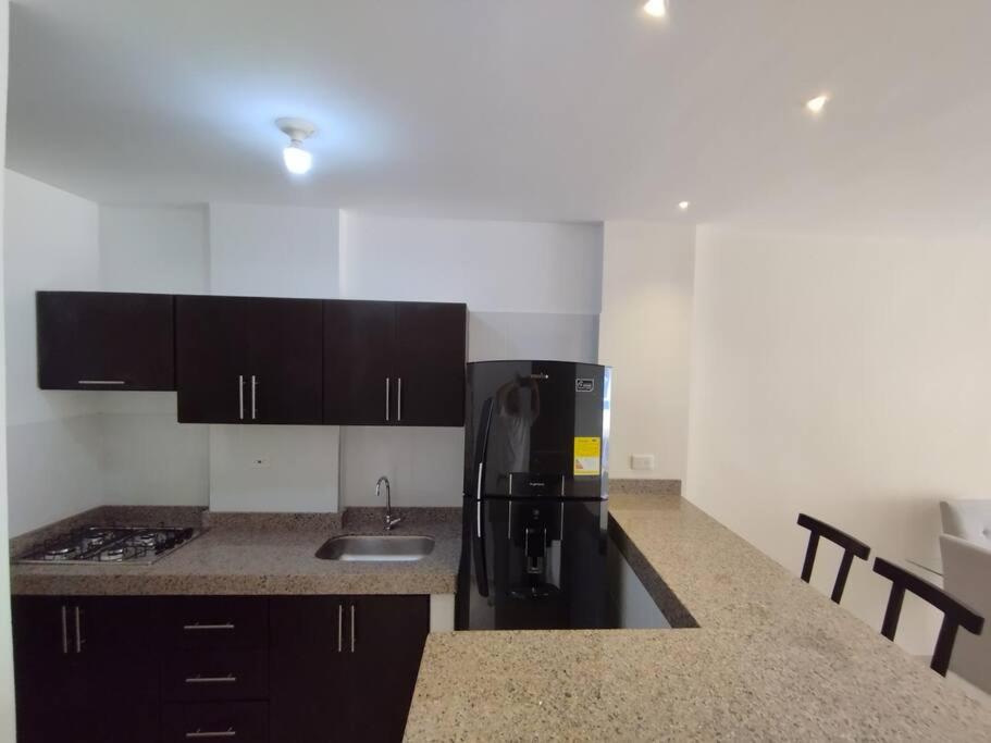 a kitchen with a black refrigerator and a sink at Edificio Verona 57 - Apartamento en Piedecuesta in Piedecuesta