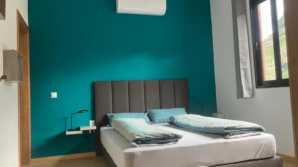 a bedroom with a blue wall and a bed with pillows at Casa Azul in São Vicente