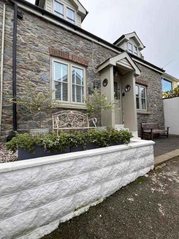 a stone house with a bench in front of it at Efail Fach in New Quay