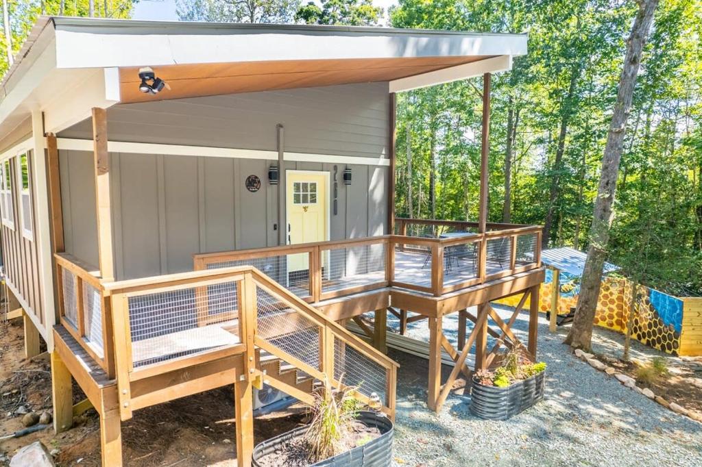 a tiny house with a porch and a deck at Elevate Tree House Community in Pittsboro