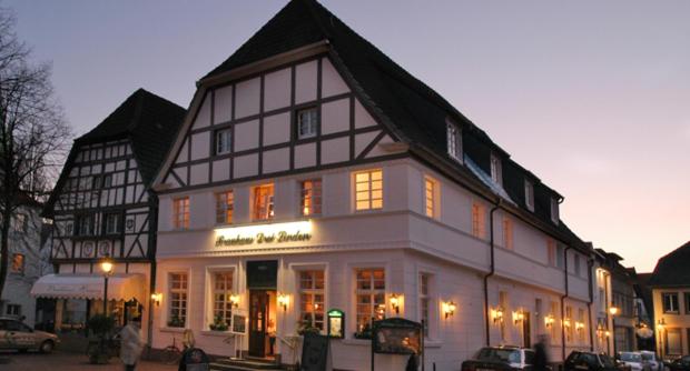 a large white and black building with lights on at Hotel Drei Linden in Lünen