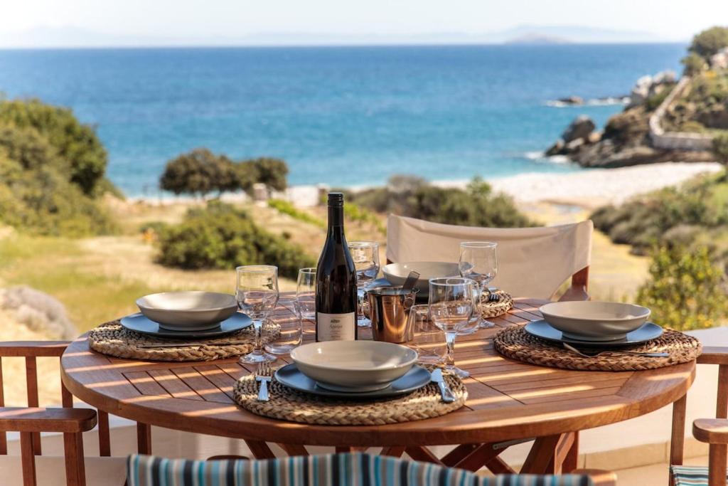 a wooden table with a bottle of wine and glasses at Apiliotis sunrise beach villa in Ligaridia