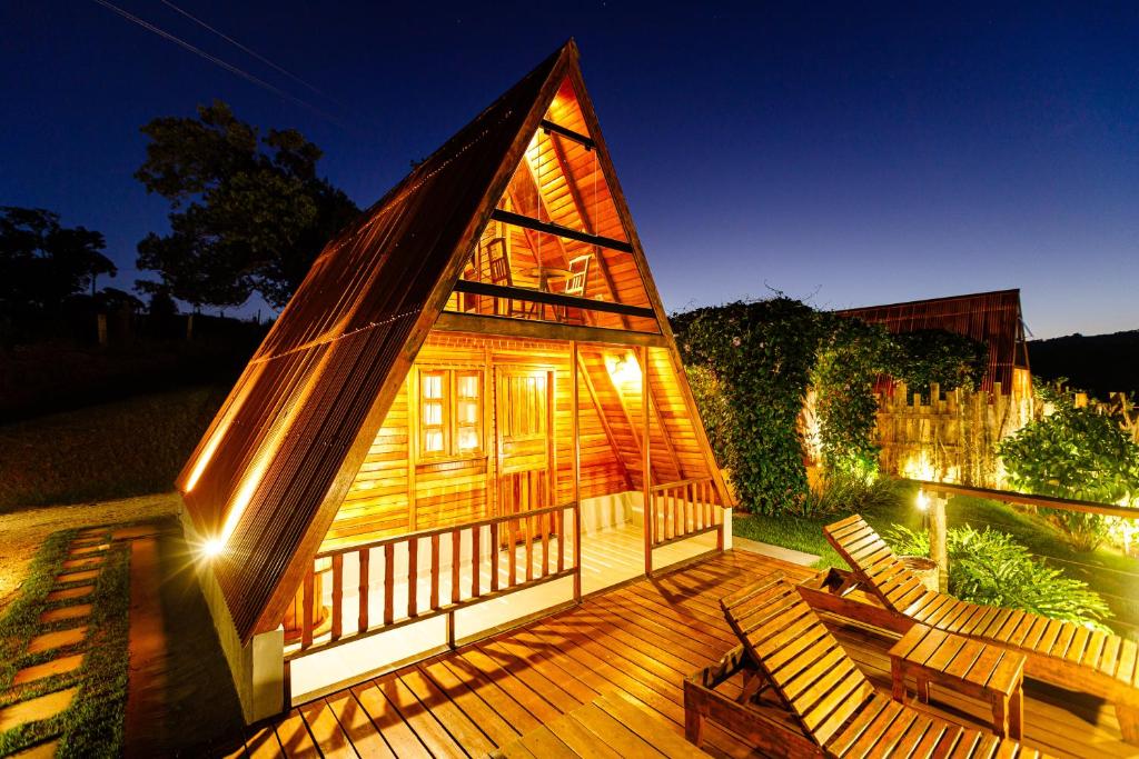 a small cabin with a deck with chairs and lights at Cabanas do Morro in Serra Negra