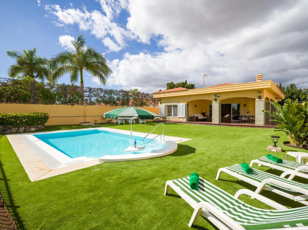 a house with a swimming pool and two lawn chairs at Golf Views Home By CanariasGetaway in Maspalomas