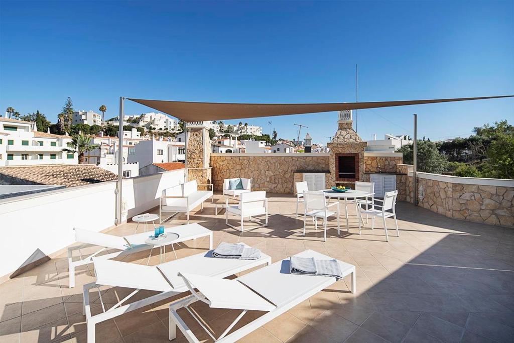 a patio with white tables and chairs on a roof at Casas de Carvoeiro by Sevencollection in Carvoeiro
