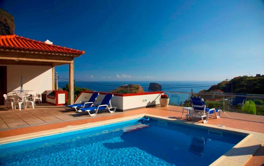 a swimming pool with chairs and a view of the ocean at Villa Ricardo in Porto da Cruz