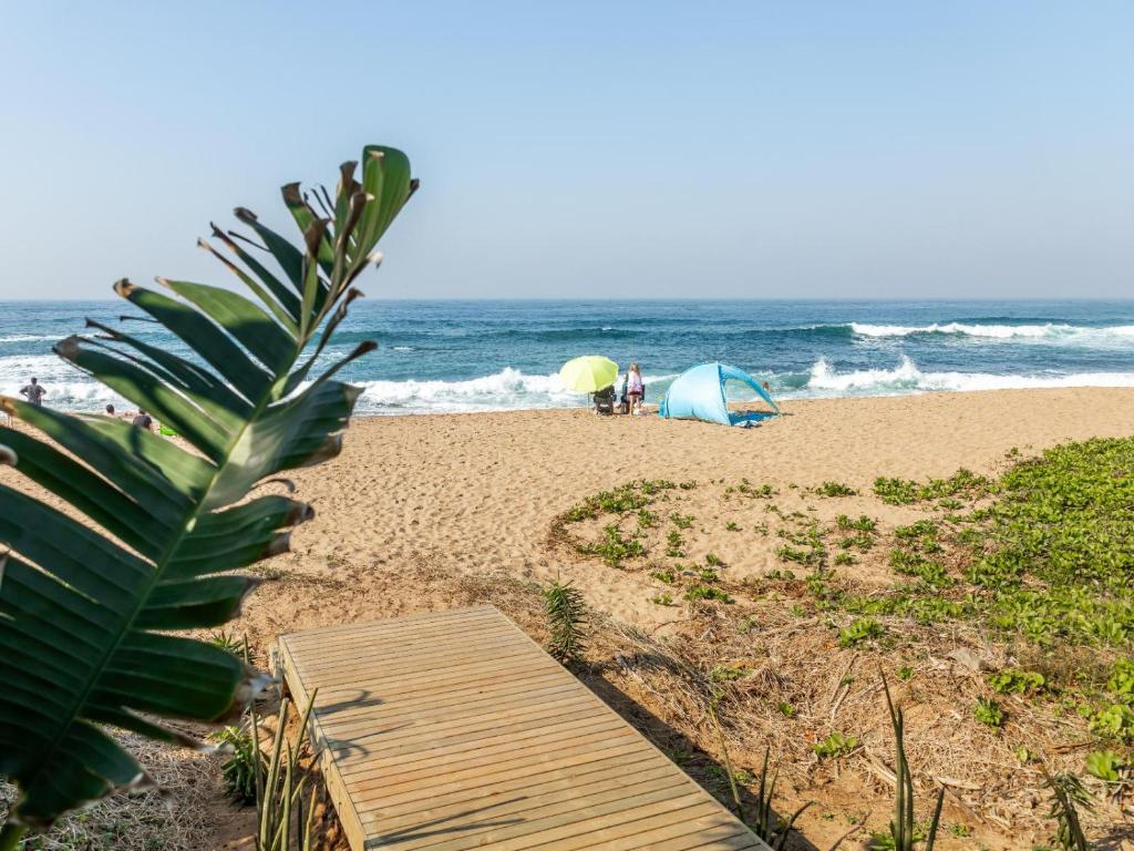 a beach with tents and people on the beach at Skiathos at Beachfront Apartments in Shakas Rock in Ballito