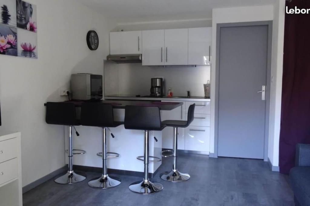 une cuisine avec des armoires blanches et des tabourets de bar dans l'établissement Joli studio rénové au cœur du village de St Lary, à Saint-Lary-Soulan