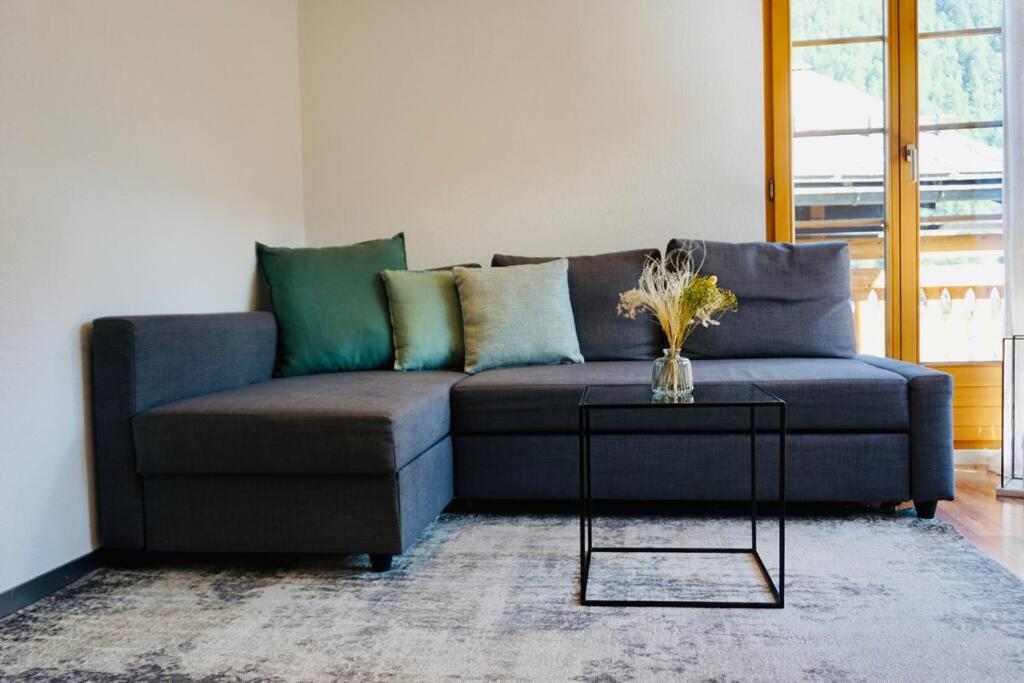 Un sofá azul en una sala de estar con una mesa. en Central Local Flat, en Zermatt