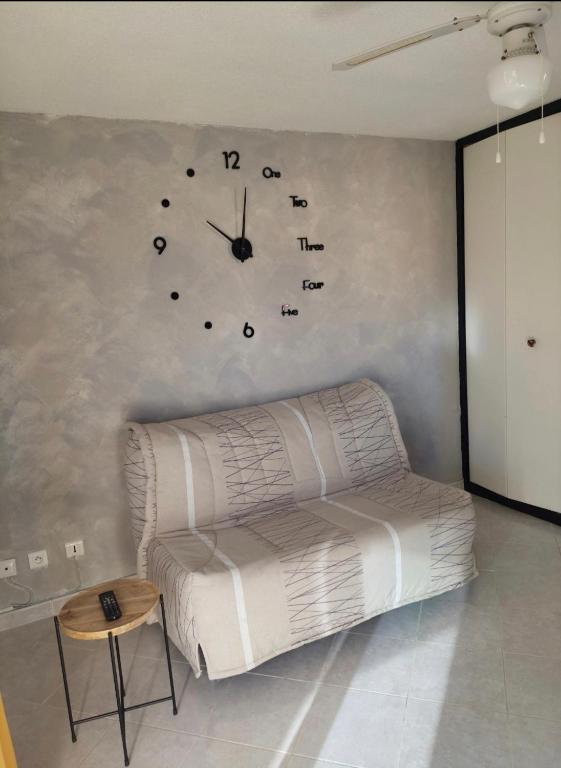 une chambre avec un canapé et un réveil sur le mur dans l'établissement Studio cabine climatisé sur l'île des pêcheurs, au Cap d'Agde