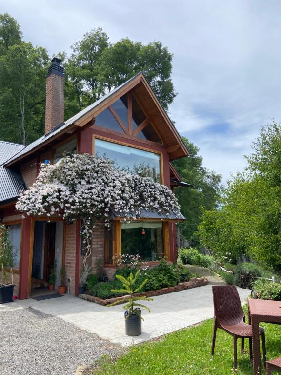 une maison avec un arbre en fleurs devant dans l'établissement Tranquera's house, à San Martín de los Andes