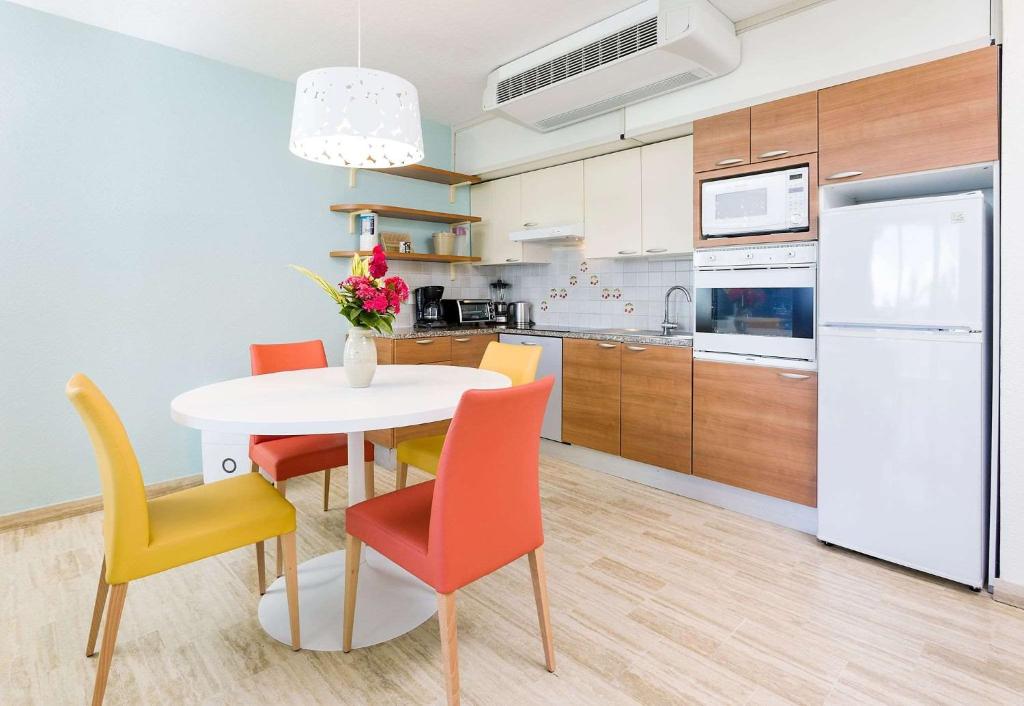 a kitchen with a white table with chairs and a white refrigerator at Royal Islander Club Resort La Plage in Lowlands