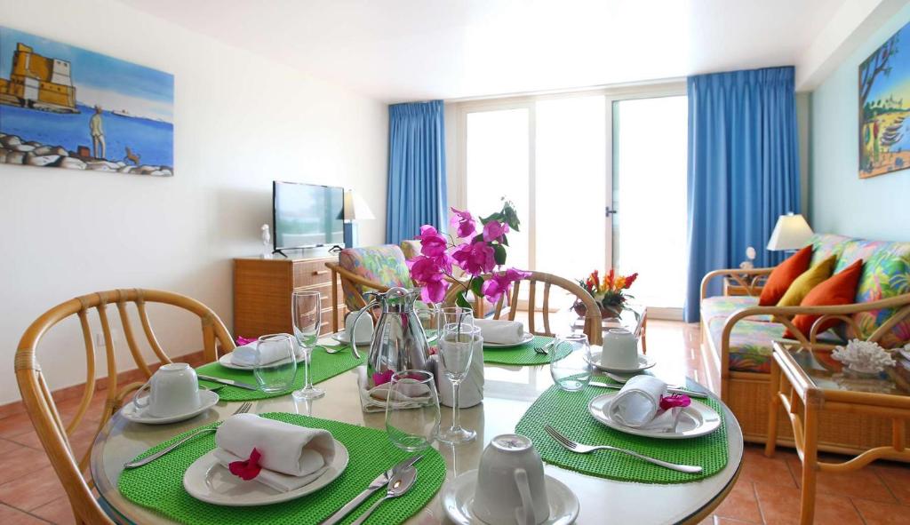 a living room with a dining room table with plates and glasses at Royal Islander Club Resort La Plage in Lowlands