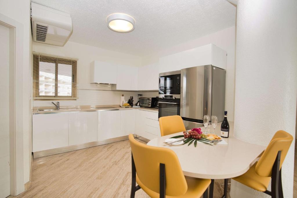 a kitchen with a white table and yellow chairs at Royal Islander Club Resort La Plage in Lowlands