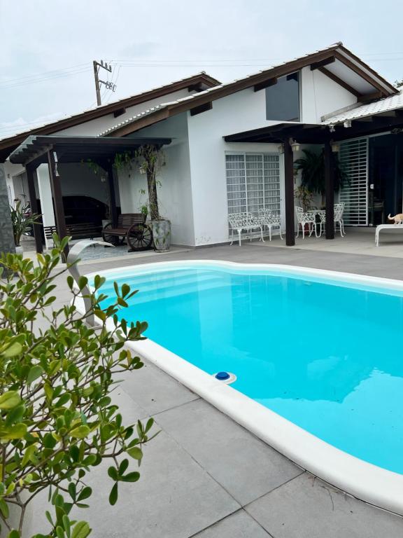 ein blauer Pool vor einem Haus in der Unterkunft Casa de praia com piscina Barra Velha in Barra Velha