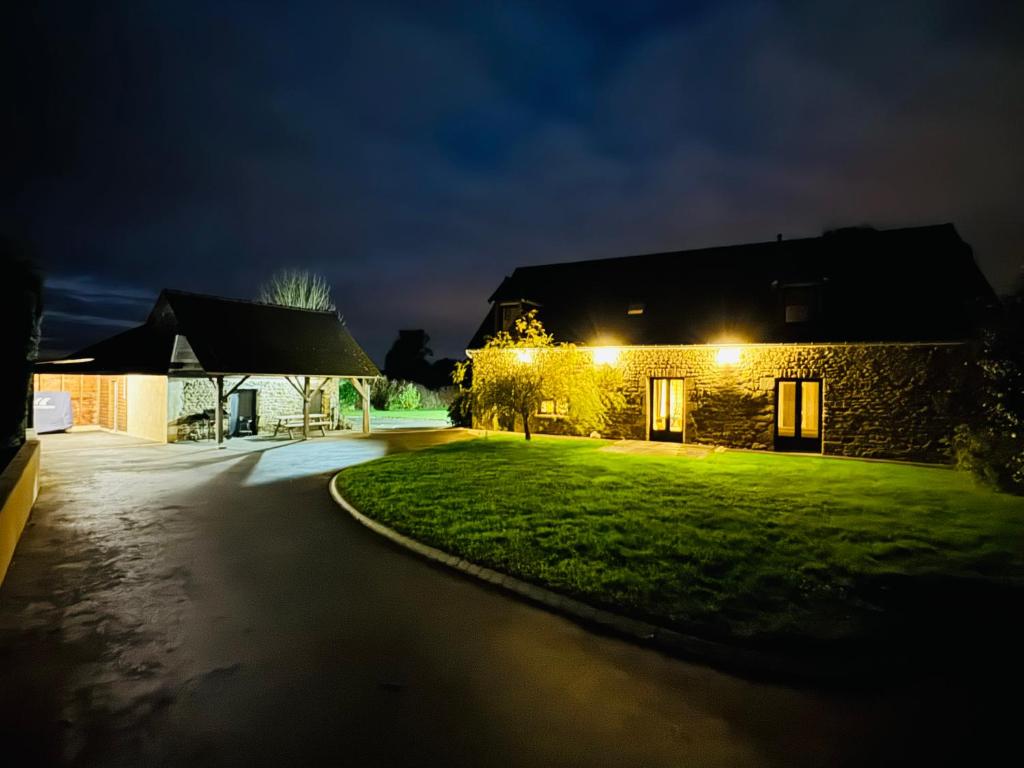 a house at night with lights on the grass at La Maison de Benjamin in La Chapelle-Saint-Aubert