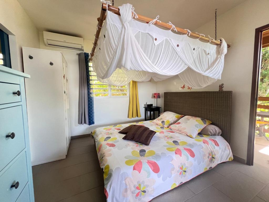 a bedroom with a bed with a canopy at Domaine Racines e Zel - Gîte PomKouli in Vieux-Fort
