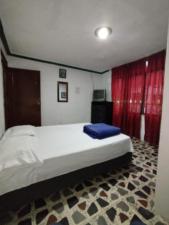 a bedroom with a large bed and a red curtain at Hostal la 18 in Pereira