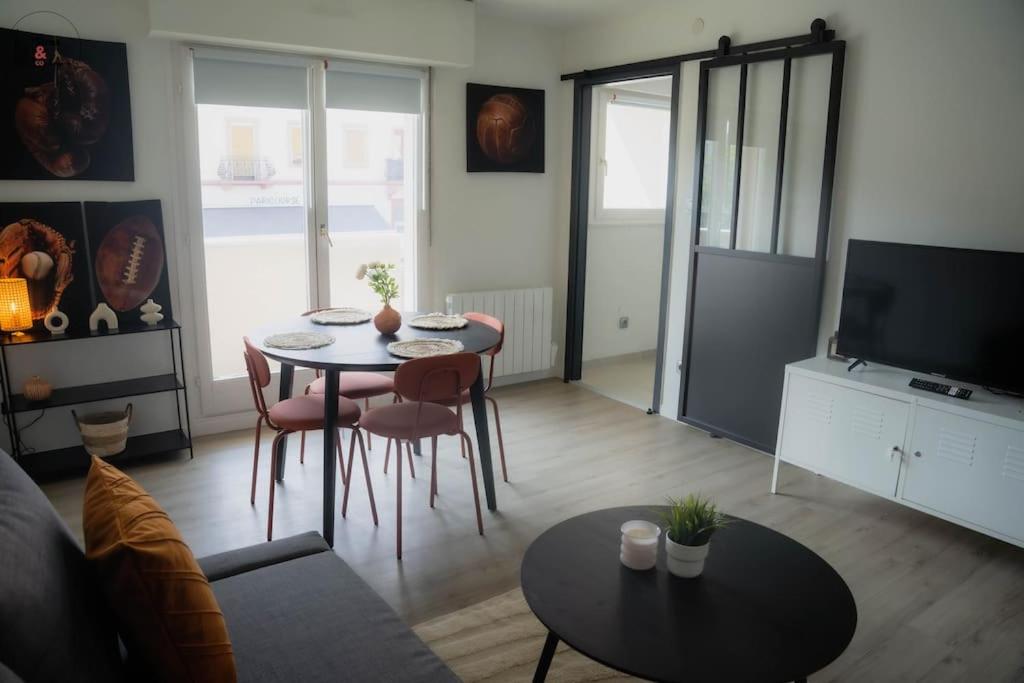 ein Wohnzimmer mit Tisch und Stühlen und einem Fernseher in der Unterkunft Charmant 2 Pièces proche Hôpital de Hautepierre in Straßburg