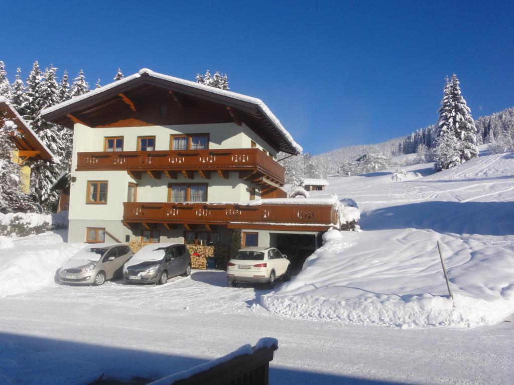 a large building with cars parked in the snow at Haus Ganschitter in Wagrain