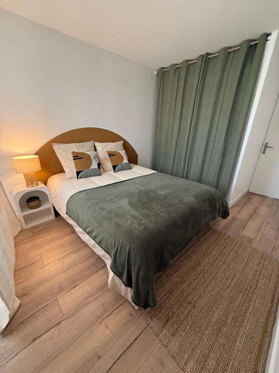 a bedroom with a bed with a green curtain at Appartement Cosy Cergy Le Haut Gare in Cergy