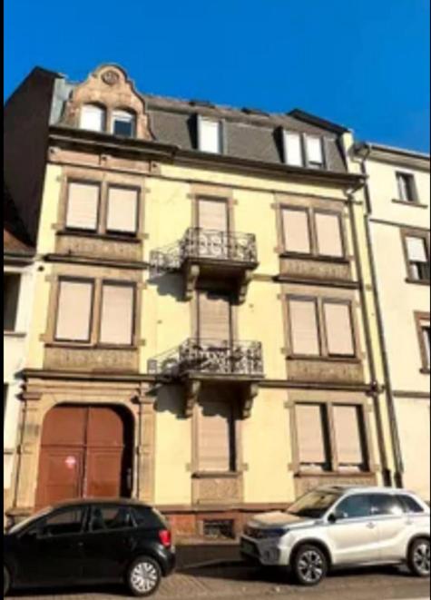 un bâtiment avec deux voitures garées devant lui dans l'établissement Appartement lumineux et cosy Strasbourg, à Strasbourg