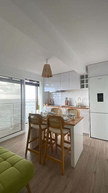 Una cocina con mesa y sillas y una cocina con vista al mar. en Wave Shadows Beach House Oceanfront property - Top Floor, en Paul do Mar