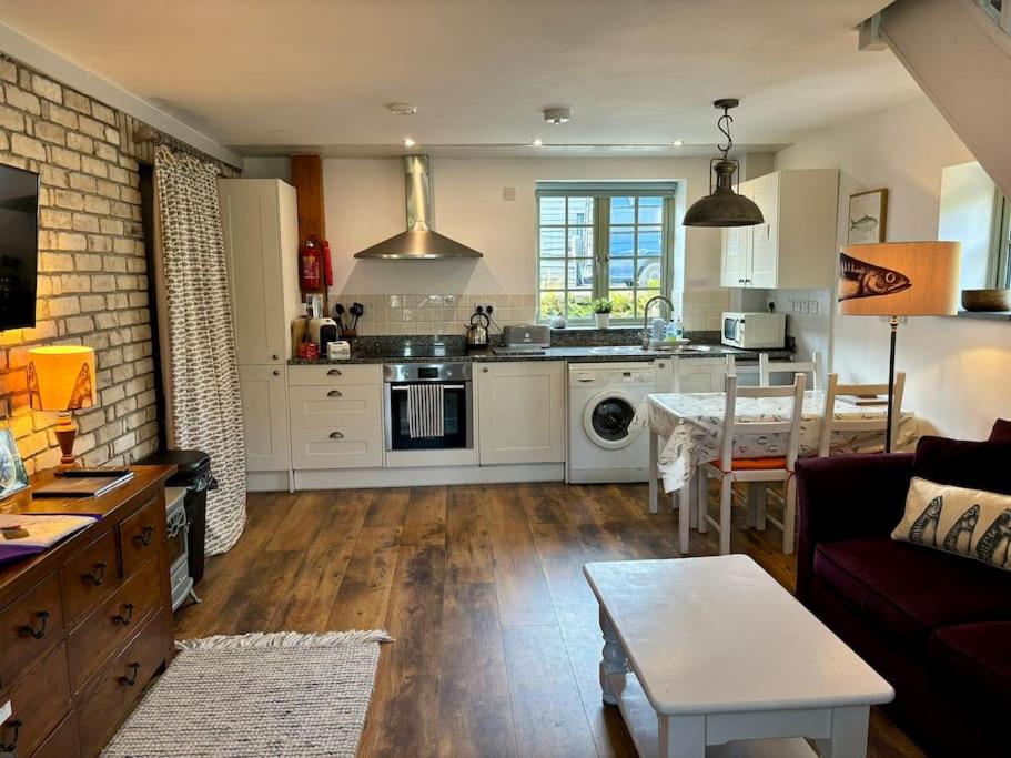 a kitchen and living room with a couch and a table at Little Bream - pretty cosy cottage, sea views, walk to the beach in Mawnan Smith