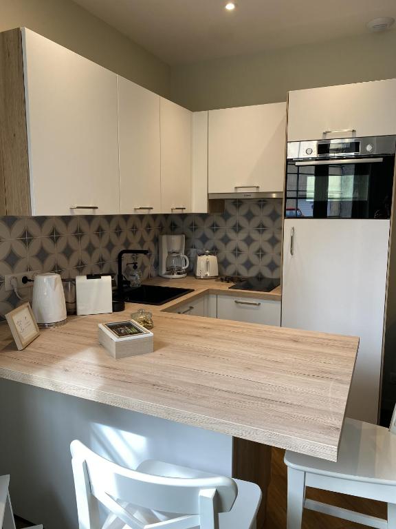 une cuisine avec des armoires blanches et un comptoir en bois dans l'établissement Marianne 1, à Bergerac