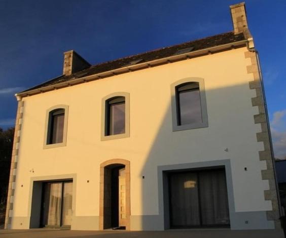 - un grand bâtiment blanc avec des fenêtres au-dessus dans l'établissement Gite de saint Antoine, à Ploudiry