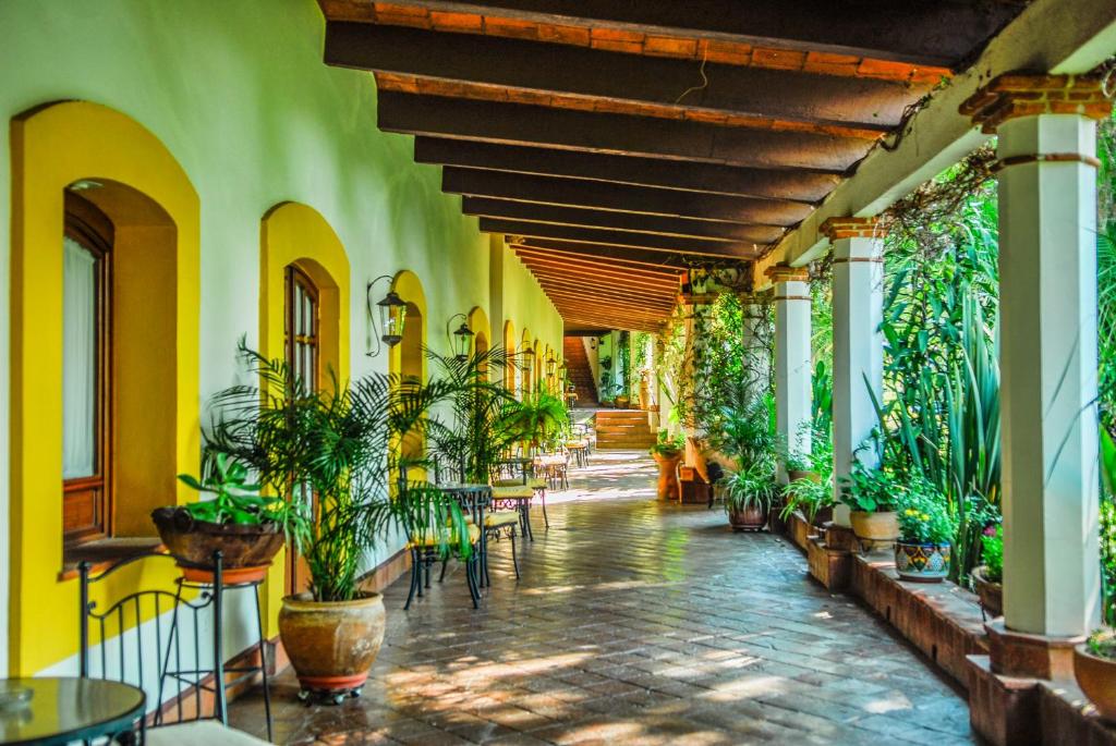 a hallway with tables and potted plants in a building at Hotel Hacienda Los Laureles in Oaxaca City