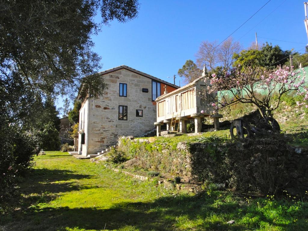 una vieja casa de piedra en una colina con un patio en Casa El Fontán, en Moaña