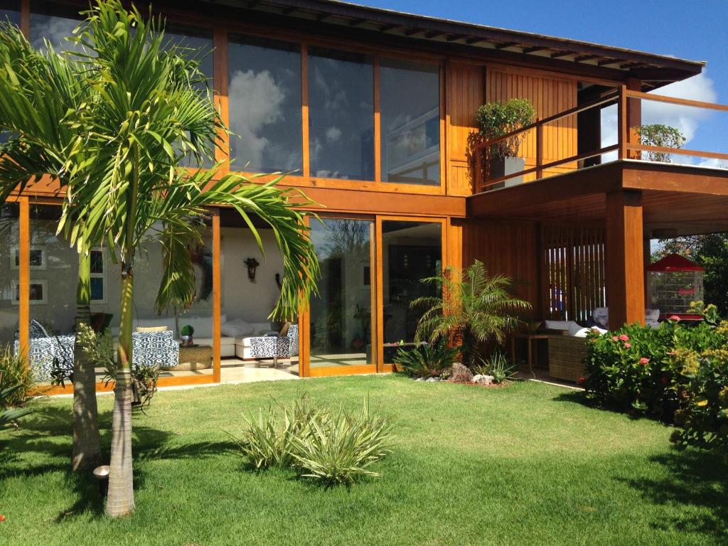 a house with a palm tree in the yard at Casa das Acácias in Praia do Forte