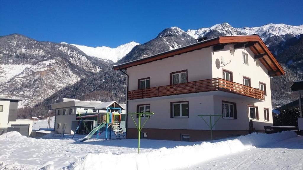 een huis in de sneeuw met bergen op de achtergrond bij Haus Attos in Umhausen