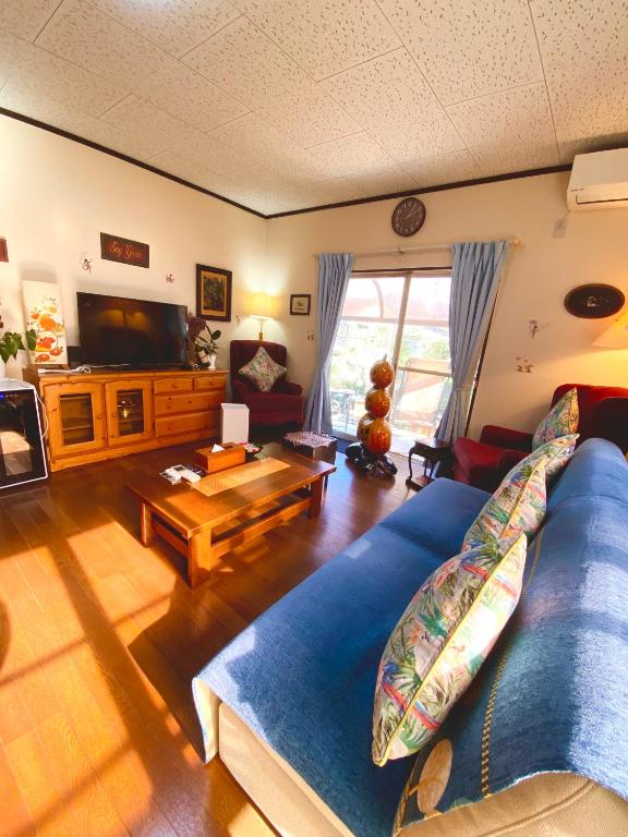 a living room with a blue couch and a television at Grace House グレイスハウス- Country Home Relaxation in Okawa
