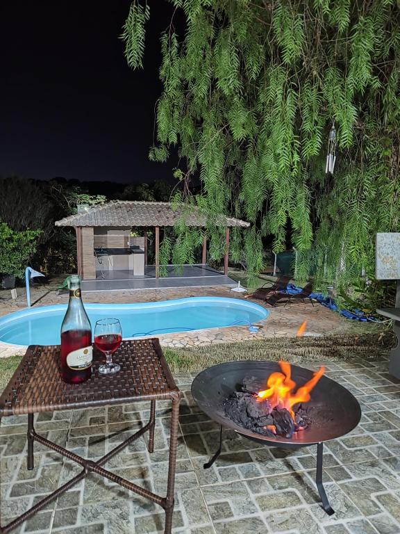 a fire pit with a glass of wine next to a pool at Sitio Lugar de Descanso em Lagoa Santa in Jaboticatubas