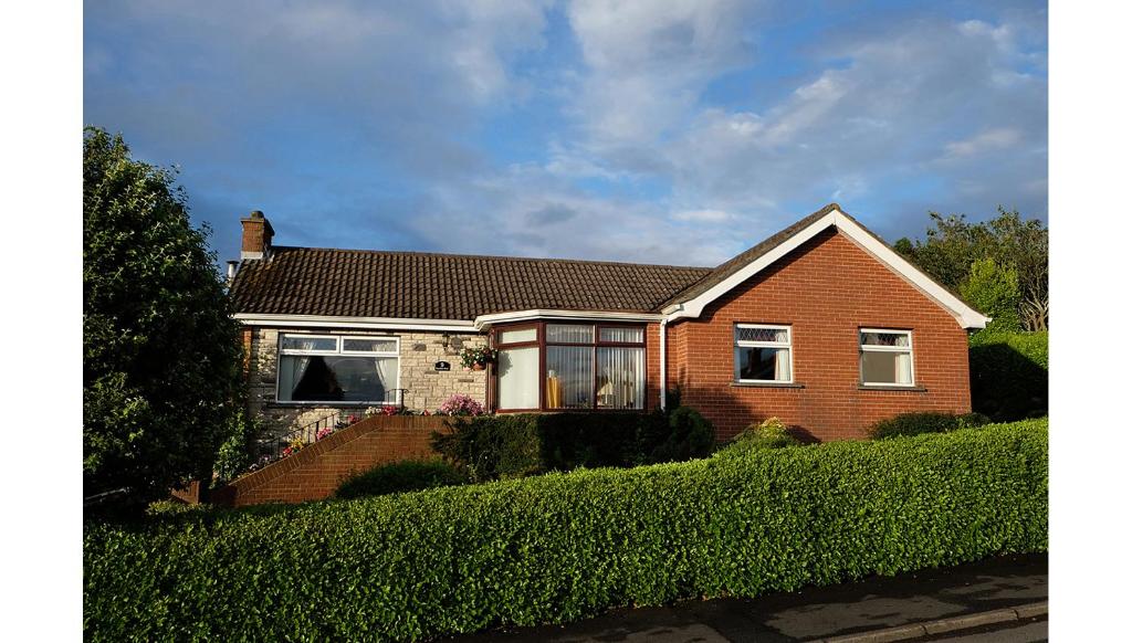 a red brick house with windows and a hedge at Number Nine Accommodation in Downpatrick