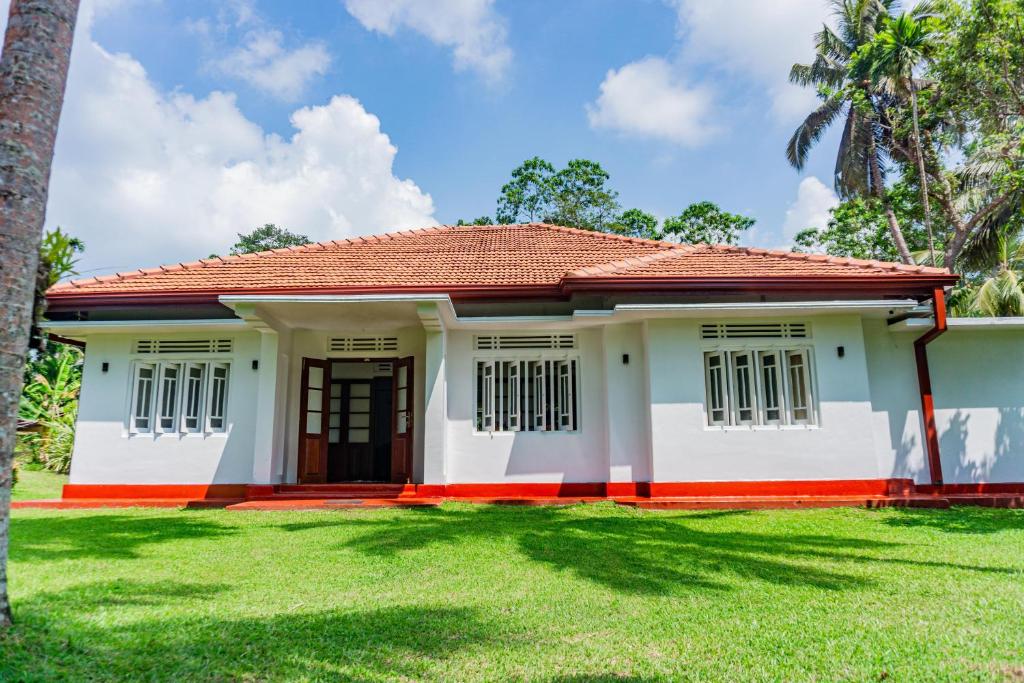 une maison avec une pelouse verte devant dans l'établissement Red Araliya Villa Weligama, à Weligama