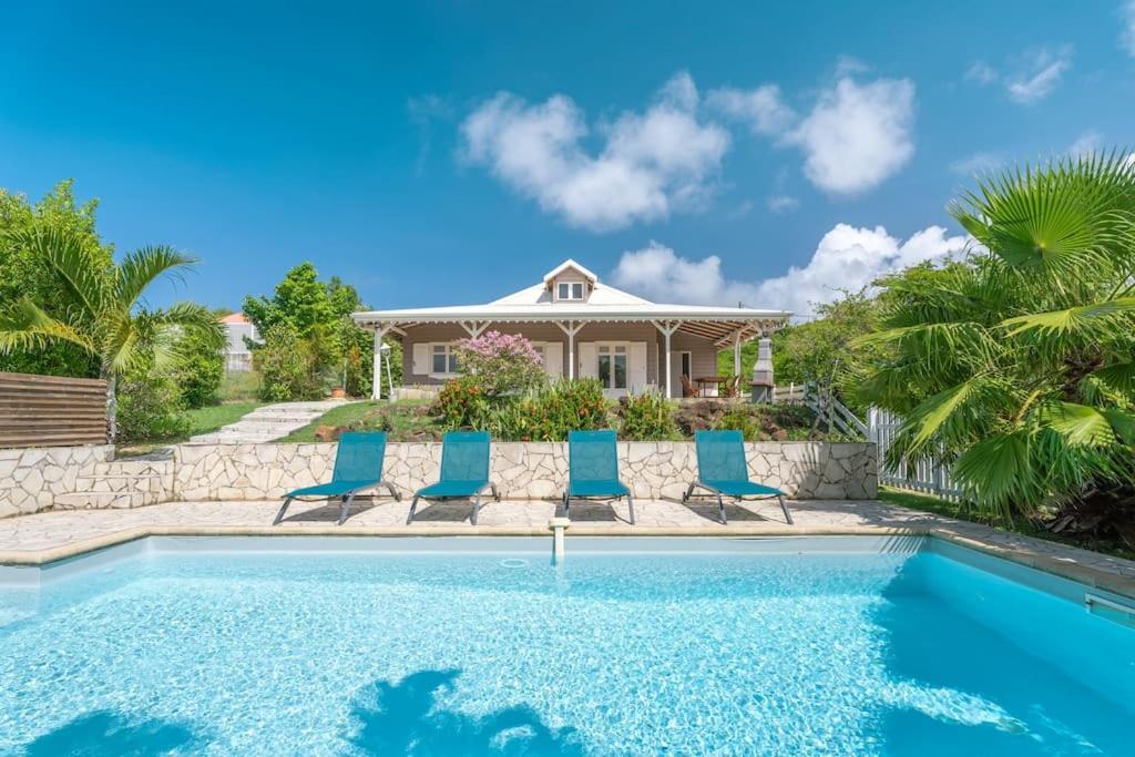 a house with a swimming pool and blue chairs at Villa Ayiana, magnifique villa avec piscine in Sainte-Anne