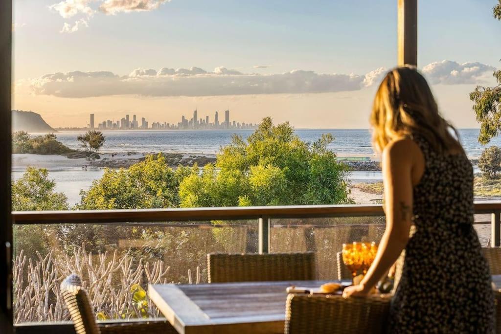 une femme debout sur un balcon regardant l'océan dans l'établissement Currumbin Beachside Retreat, à Gold Coast