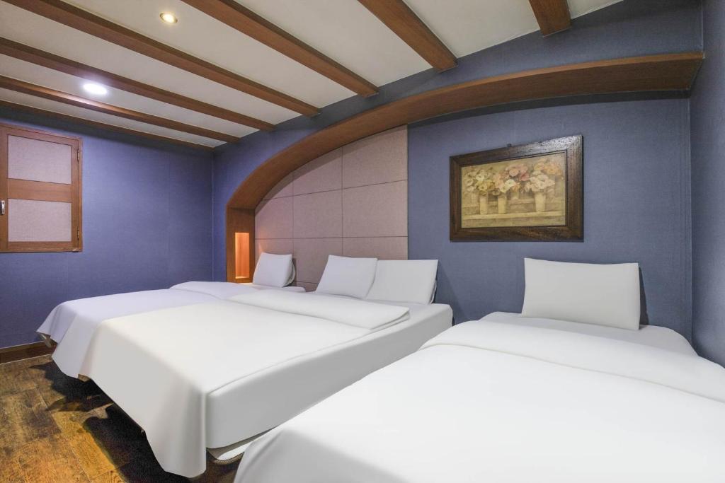 two beds in a room with blue walls at Hotel Tate V in Suwon