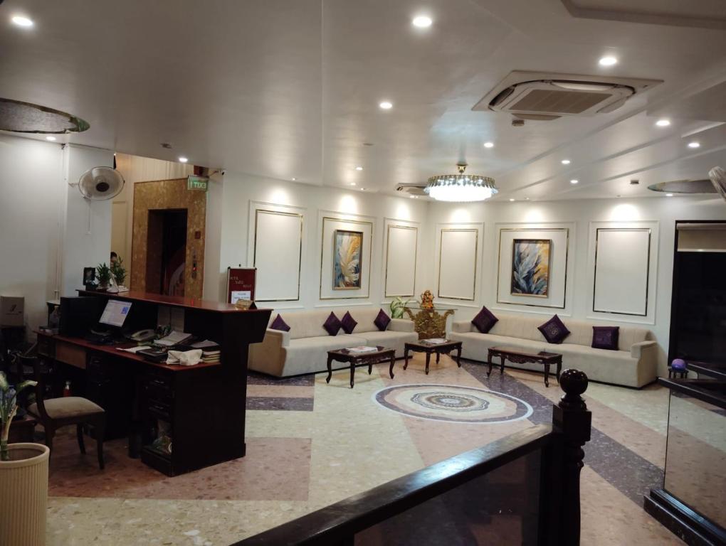 a large room with couches and a desk and a television at HotelMaple Ridge in Tājganj